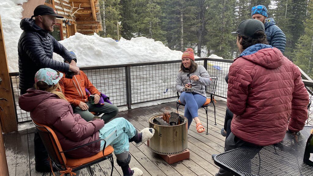 Guests enjoying coffee and mountain views from the porch at Hayden Backcountry Lodge.